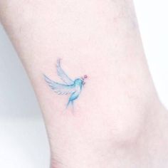 a small blue bird tattoo on the right side of the ankle, it has a tiny pink dot at the bottom