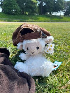 a stuffed animal with a hat on sitting in the grass