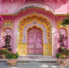 an ornate pink and yellow building with potted plants on either side of the door