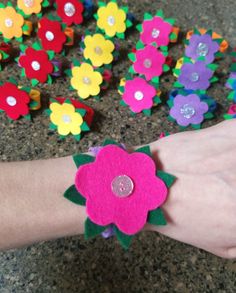 a person's hand with a flower on it and many other flowers in the background