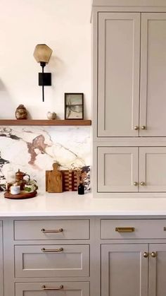 a kitchen with white cabinets and marble counter tops, gold pulls on the cupboards