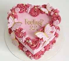 a heart shaped cake with pink frosting and gold decorations on top that says feeling 22