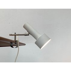 a white wall mounted lamp with a wooden arm and light bulb on the left side