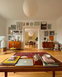 a living room filled with lots of furniture and pictures on the wall next to a coffee table