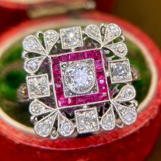 This finely early Art Deco diamond and ruby ring has been handmade in platinum. It's from the 1920s when jewellers still displayed the most extraordinary, painstaking skill in working platinum to almost spiderweb delicacy - as shown by the underside as well as the top of this lovely ring. (I like the "lucky 88" in the under-rail, by the way.) The square shapes and the calibre cut rubies put it in the Art Deco period.  The rubies are synthetic. This is common for the era - it was done to achieve Red Victorian Diamond Ring, Art Deco Ruby Jewelry With Brilliant Cut, Art Deco Ruby Ring With Brilliant Cut Diamond, Art Deco Ruby Ring With Rose Cut Diamonds, Art Deco Style Round Ruby Ring With Diamonds, Art Deco Ruby Ring With Diamond, Art Deco Diamond Ruby Ring With Round Cut, Art Deco Ruby Rings With Brilliant Cut, Vintage Silver Ruby Ring With Diamond