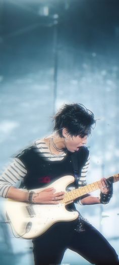 a man with black hair playing a white guitar