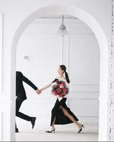 a man and woman holding hands in an archway with flowers on the floor next to each other