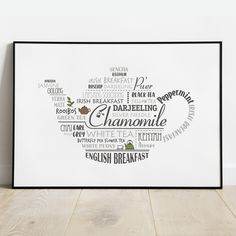 a white framed poster with words in the shape of a teapot on a wooden floor