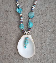 This is a blue & turquoise color beaded necklace, made with shells, pearl, acrylic, and glass beads.  The skulls on the necklace are made out of stone.  Inspired by spiritual ceremonies the holistic effects of this necklace provides protection from outside sources, along with balancing and aligning all chakras, stabilizing mood, and instilling an inner calm.  Necklace Measurements:  Length: 24" Pendant Height: 2.5" Pendant Width: 2" If you have any questions or would like to see additional pictu Turquoise Shell Round Bead Jewelry, Turquoise Beaded Necklaces With Round Beads, Ocean-inspired, Turquoise Beaded Shell Jewelry, Turquoise Shell Beaded Necklaces, Turquoise Shell Beaded Necklaces With Round Beads, Blue Shell Jewelry With Colorful Beads, Turquoise Beaded Necklace, Ocean-inspired, Ocean-inspired Turquoise Beaded Necklaces, Turquoise Ocean-inspired Beaded Necklace With Round Beads