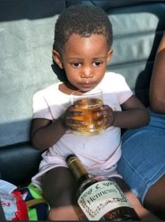 a little boy sitting on the back of a car holding a jar of honey in his hands