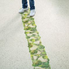 a person is standing on the sidewalk with their feet in the air and there are trees painted on the pavement