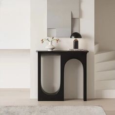 a modern console table with vases on it in front of a mirror and stairs