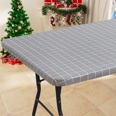 a table with a gray tiled top in front of a christmas tree