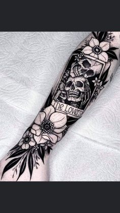 a black and white tattoo with flowers on the arm, skull and banner that says it's love