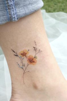 a small flower tattoo on the side of a woman's leg, with leaves and flowers