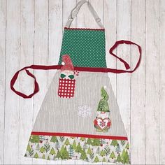 two aprons with christmas decorations on them hanging from the side of a wooden wall