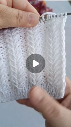 someone is stitching the side of a white knitted piece with a crochet hook