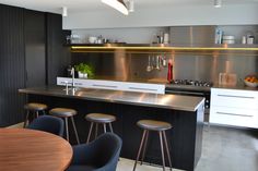 a modern kitchen with stainless steel counter tops and bar stools