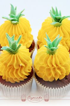 two cupcakes with yellow frosting and green leaves on top are sitting side by side