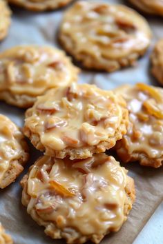 some cookies with icing and nuts are on a piece of wax paper in front of them