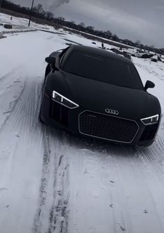 a black car driving down a snow covered road