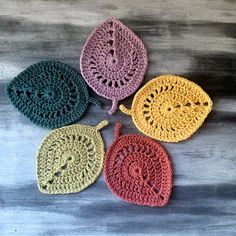 four crocheted doily are shown on a wooden surface, each with a different color