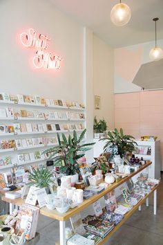 the inside of a small shop with many items on display and plants in vases