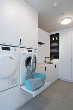 a washer and dryer in a white laundry room with built - in cabinets