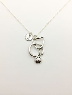 a silver necklace with three charms hanging from it's sides on a white surface