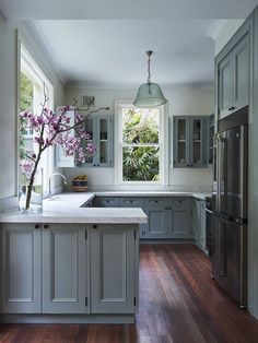 a large kitchen with wooden floors and gray cabinetry, along with a white marble counter top