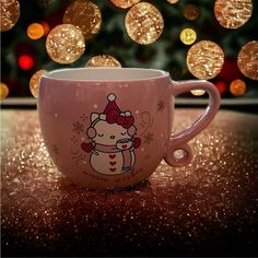 a hello kitty coffee mug sitting in front of a christmas tree