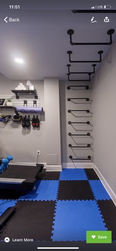 an exercise room with blue and black mats on the floor, wall mounted rack for sports equipment