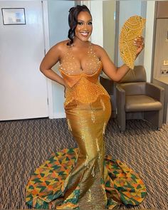 a woman in a gold and green dress holding up a leaf with her right hand