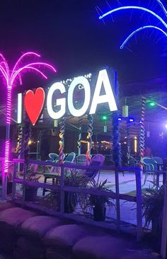 an illuminated sign that says i love goa with palm trees and lights in the background