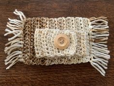 a close up of a knitted object on a wooden surface with a button in the center