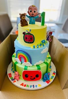 a three tiered cake with cartoon characters on it in a box at a birthday party