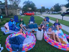 a group of people sitting on inflatable lounge chairs outside at dusk with drinks and snacks