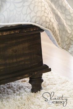 a bed with a wooden headboard and foot board sitting on top of a white rug