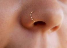 a woman's nose with a gold nose ring on her left side, and the end