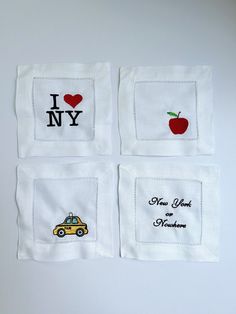 four napkins with embroidered designs on them, each featuring an apple and the words i love new york