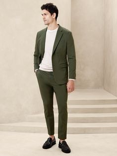 a man in a green suit stands on some steps and looks off to the side