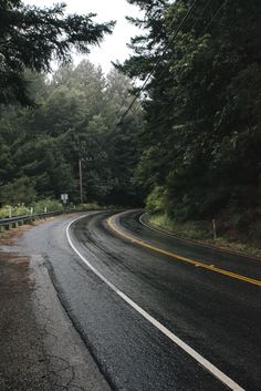 an empty road surrounded by trees and power lines