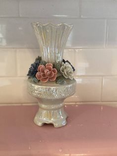 a glass vase with flowers in it sitting on a pink counter