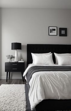 a black and white bedroom with a bed, night stand, rug and pictures on the wall