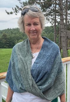 an older woman standing on a porch next to a tree