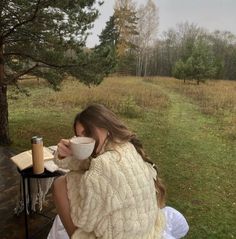 a woman sitting on a bench holding a coffee cup and looking at the ground in front of her