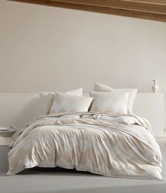 a bed with white sheets and pillows in a room