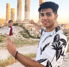 a man standing in front of some ancient ruins with his hand up to the camera