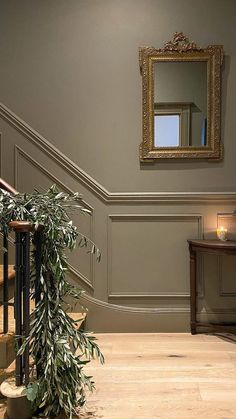 a plant is sitting on the floor in front of a mirror and stair railings