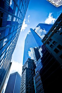 skyscrapers in new york city with blue sky and clouds above them, looking up at the